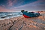 Farebná loď na piesočnatom pobreží za súmraku
